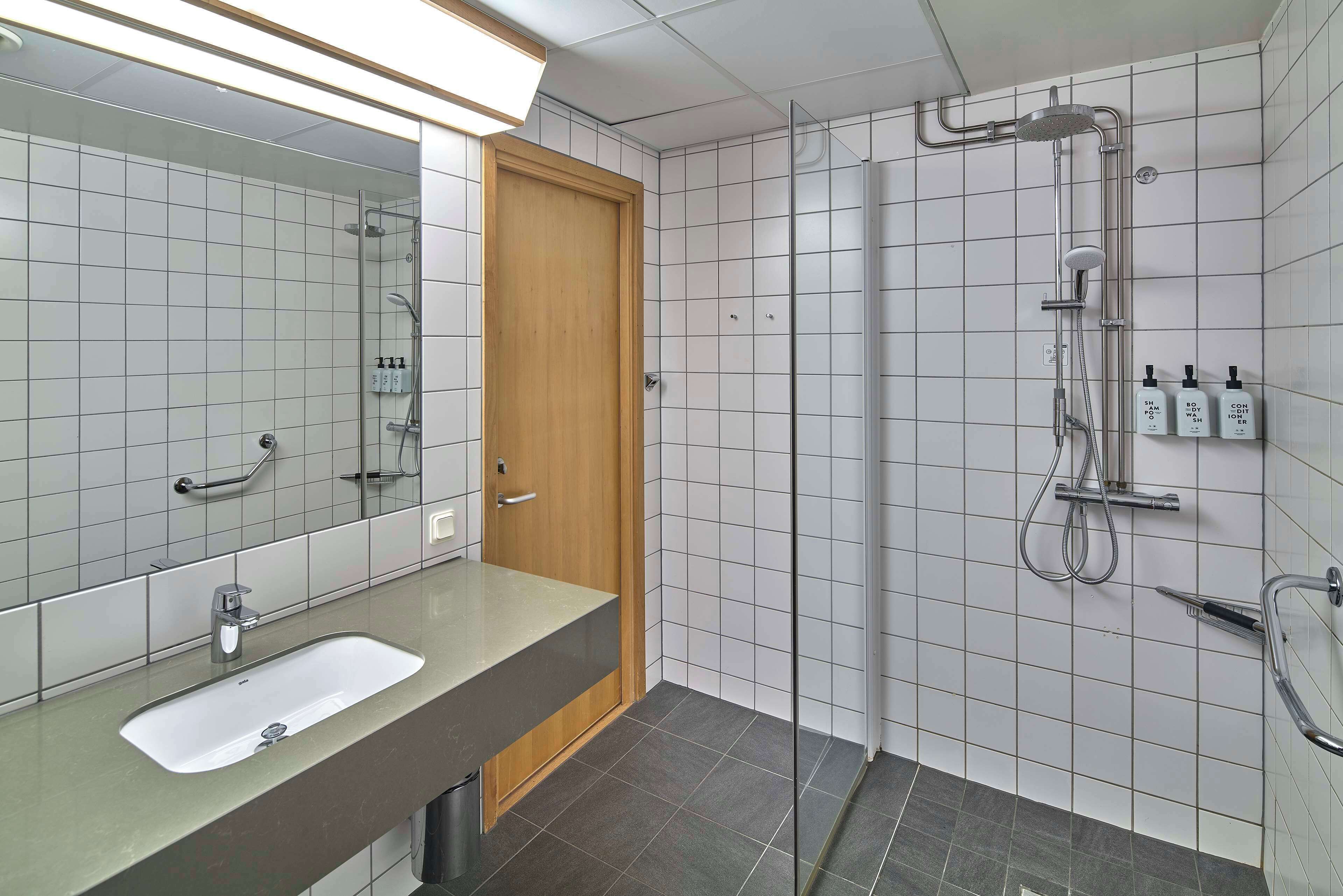 Ein modernes Badezimmer mit Waschbecken, Spiegel, Dusche und Fliesen.