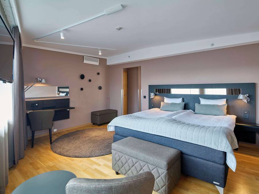 Un dormitorio moderno con una cama grande, un escritorio y una silla.