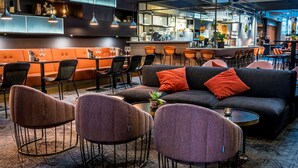 Un restaurante moderno con zona de bar, mesas y un mostrador.
