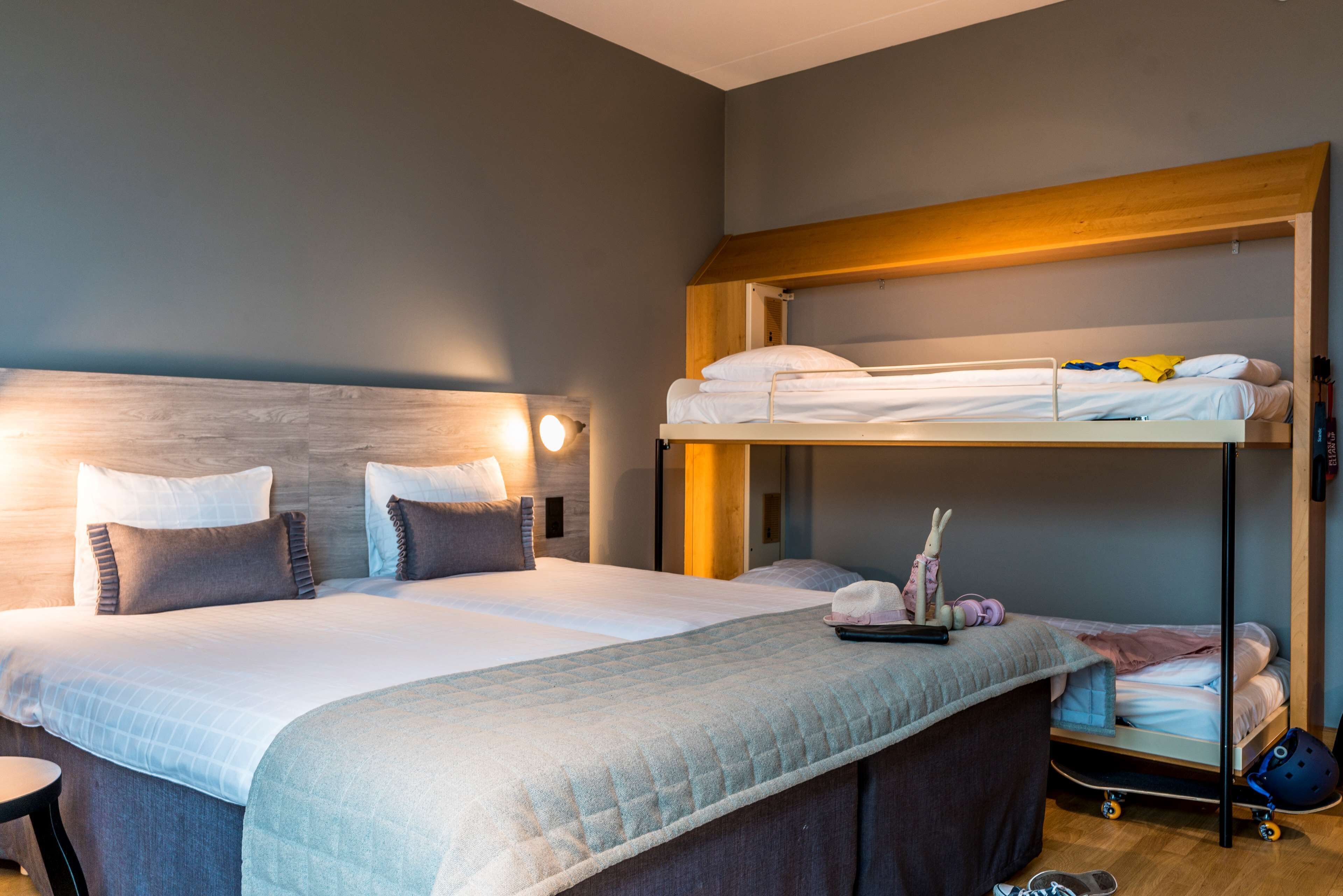 Een hotelkamer met een groot bed, een stapelbed, een nachtkastje en een klein bureau.