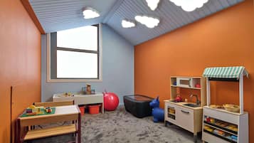 Children can play and learn in this vibrant playroom with a play kitchen, storage solutions, and a variety of play equipment.