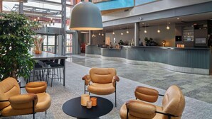 Un vestíbulo amplio con sillones de cuero, una mesa central y una gran lámpara colgante.
