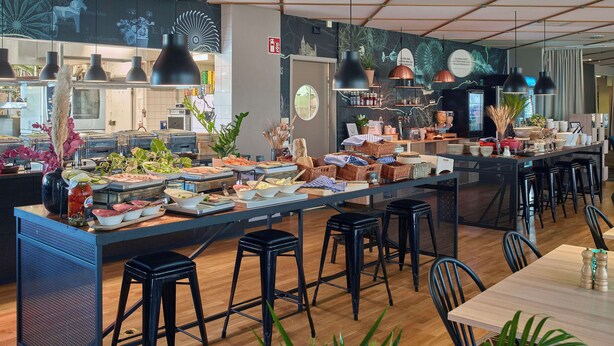 Un área de bufé con diferentes opciones de comida y un espacio de comedor con taburetes y mesas.