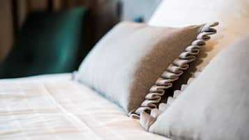 Primer plano de una cama con un almohadón ordenado y un cojín con volantes.