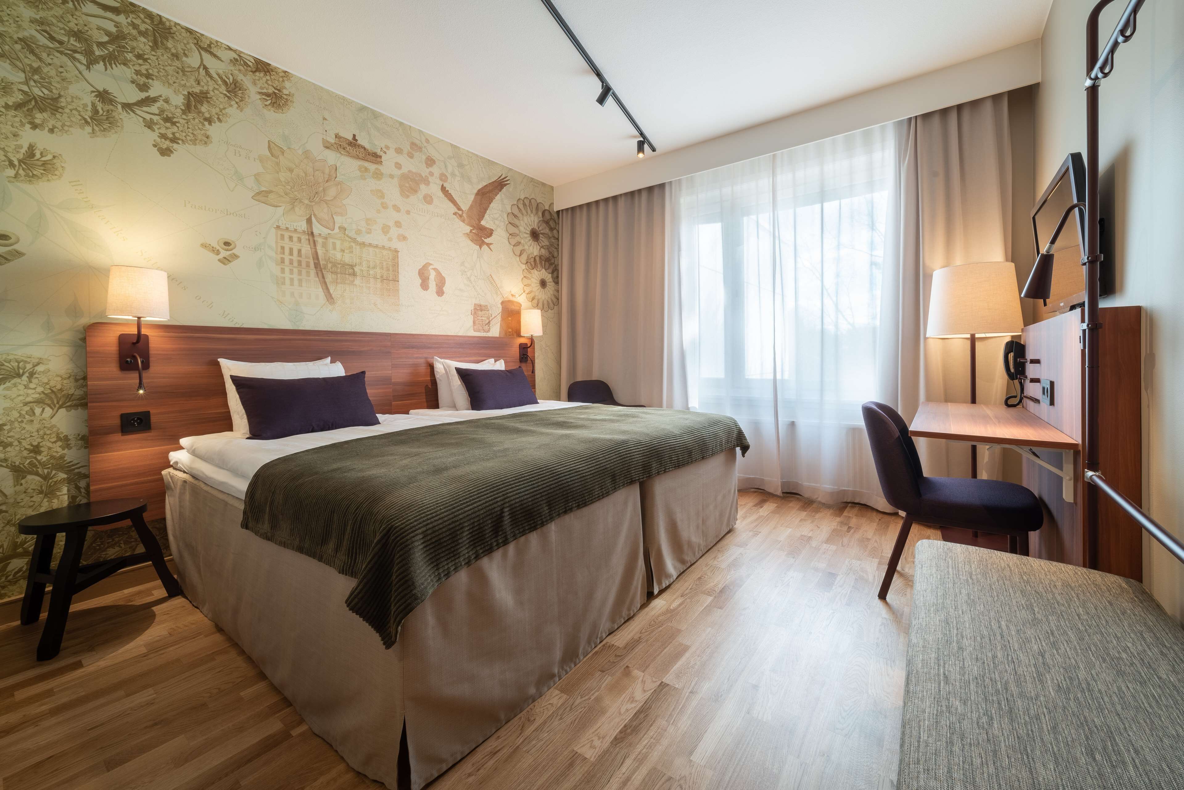 Habitación de hotel con una cama grande, un escritorio, una silla y una lámpara.