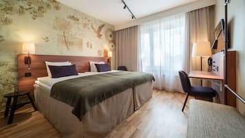 Habitación de hotel con una cama grande, un escritorio, una silla y una lámpara.