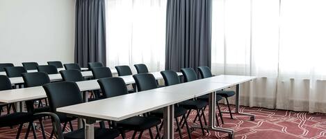 A conference room with a long table, multiple chairs, and a carpeted floor.