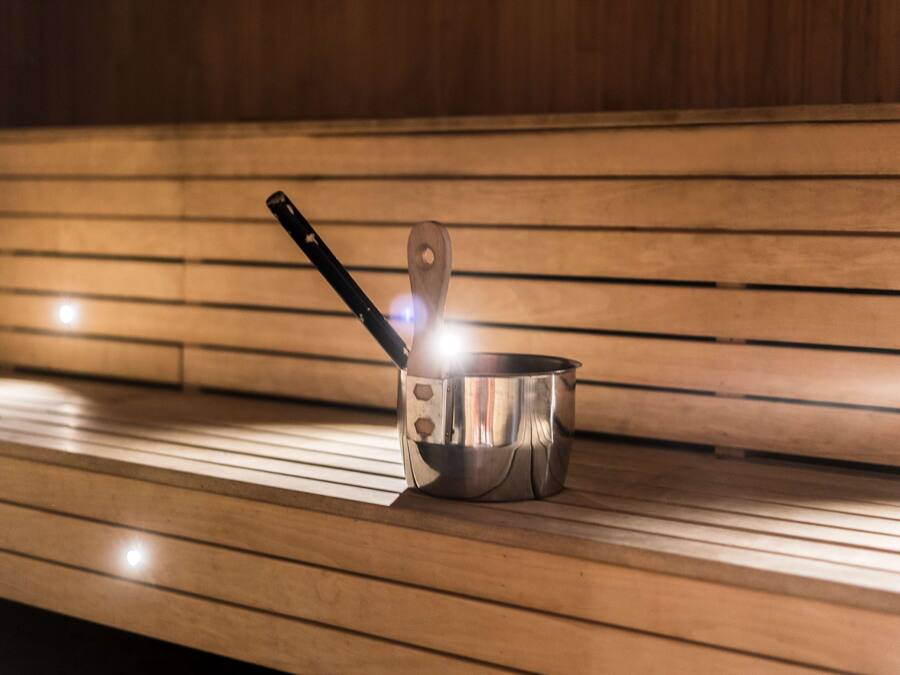 A stainless steel pot with a wooden handle on a wooden bench.