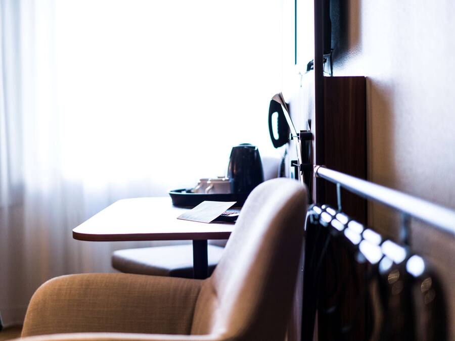 Una habitación de hotel con una cama, una mesita de noche y una silla.
