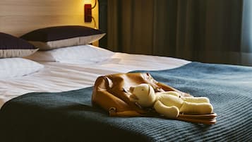 A bed with a brown leather bag and a plush toy on a dark blue bedspread.