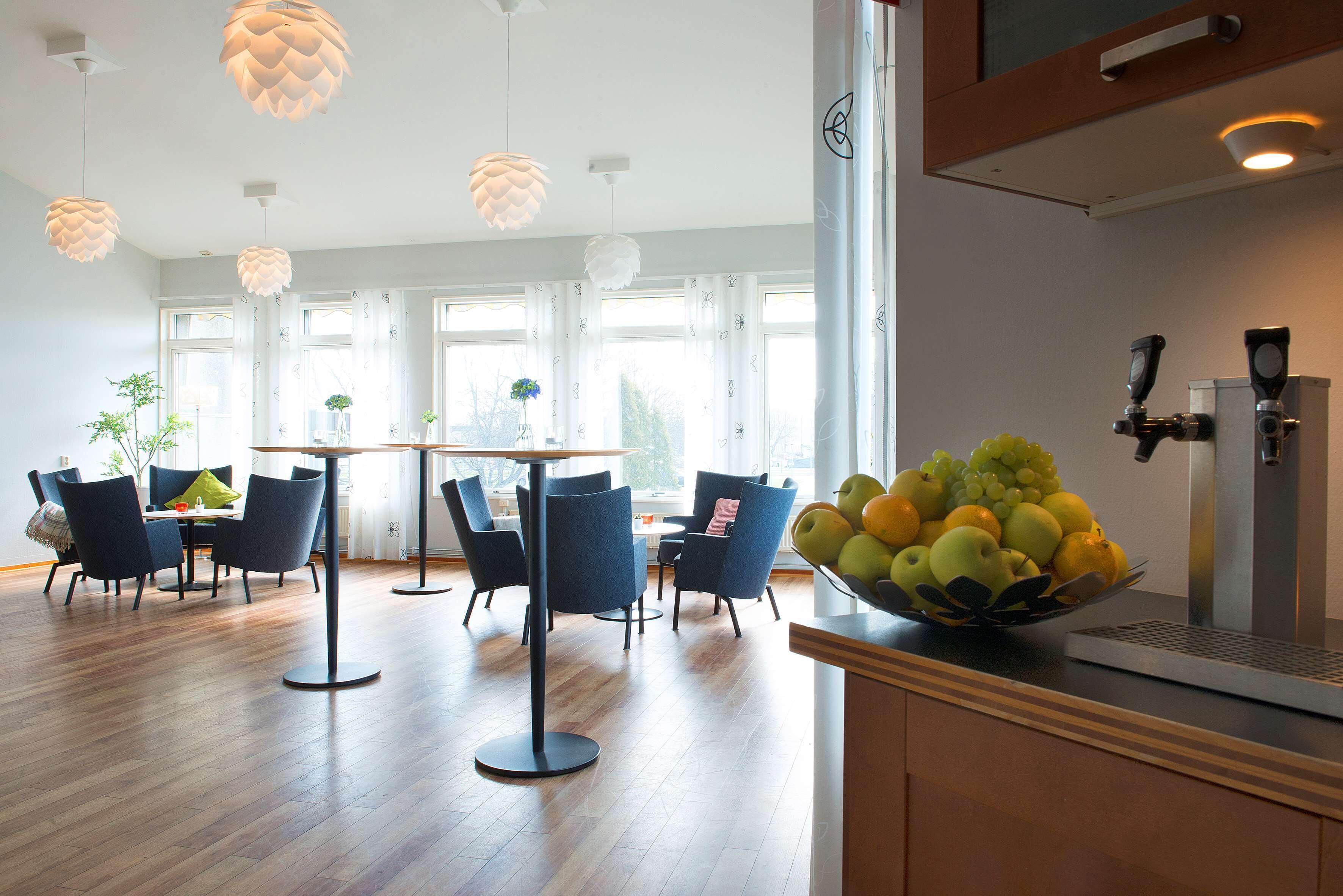 A modern dining area with a round table and chairs, a fruit bowl on the counter, and a coffee machine.