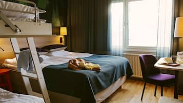 Una habitación de hotel con literas, un escritorio con silla, una lámpara y una ventana con cortinas.