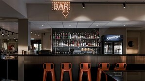 Zona de bar con un letrero que dice 'BAR', un letrero de 'Spendrups' y una variedad de botellas de licor en estantes.