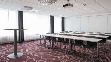 A conference room with a long table, chairs, and a projector.