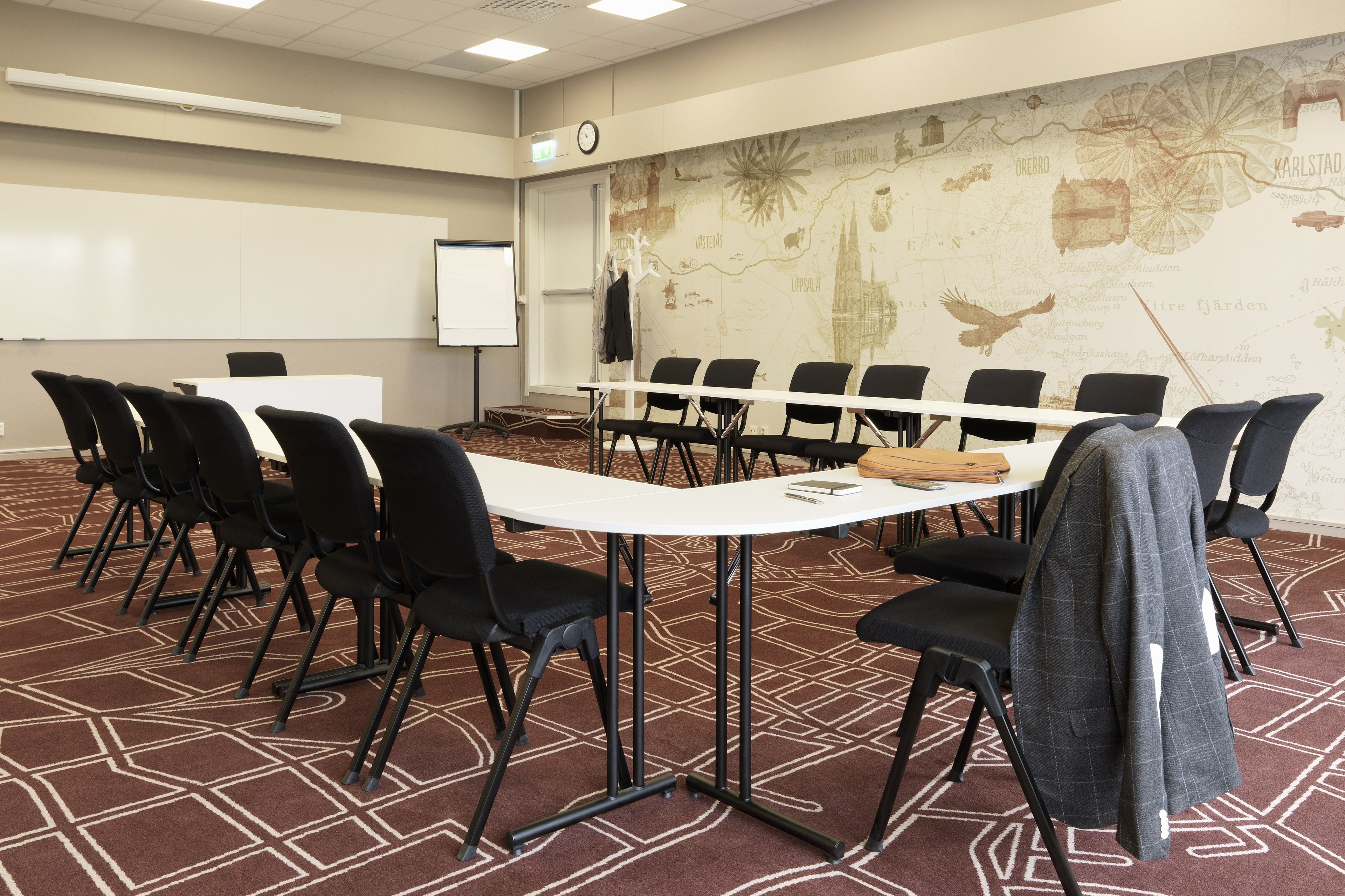 Ett konferensrum med ett långt bord, svarta stolar, en whiteboard och en karta på väggen.