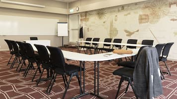 Ett konferensrum med ett långt bord, svarta stolar, en whiteboard och en karta på väggen.