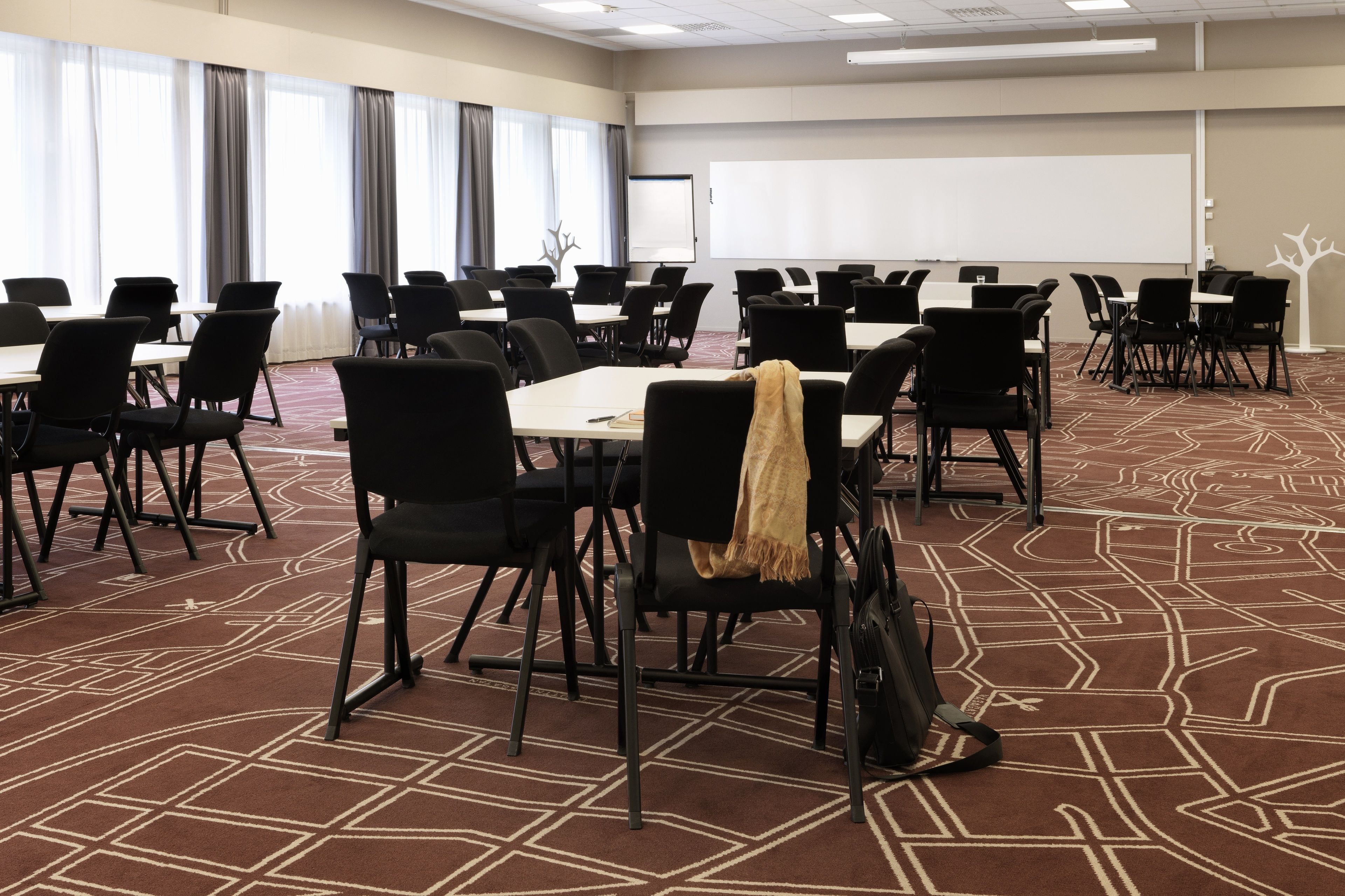 Una sala de conferencias con varias mesas y sillas, una pantalla de proyector y una pizarra.