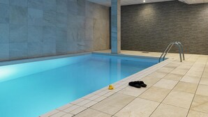 Una piscina con paredes de azulejos y una pared texturizada oscura al fondo.