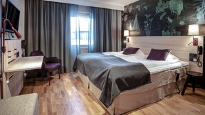 A hotel room with a bed, a desk, a chair, a TV, and a large window with curtains.