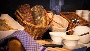 A variety of breads and pastries on a table, including a basket of loaves and small bowls of spreads.