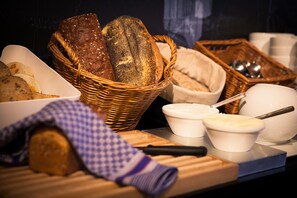 A variety of breads and pastries on a table, including a basket of loaves and small bowls of spreads.
