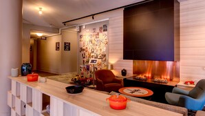 A modern living room with a wooden coffee table, a fireplace, and a wall decorated with photos. - Scandic Linköping Väst (Linkoping)
