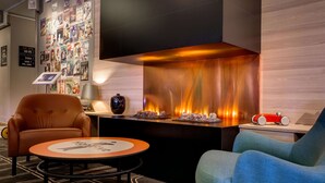 A modern lounge area with a fireplace, comfortable seating, and a wall adorned with various posters. - Scandic Linköping Väst (Linkoping)