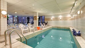 An indoor swimming pool with clear water, surrounded by white chairs and a blue decorative animal statue.