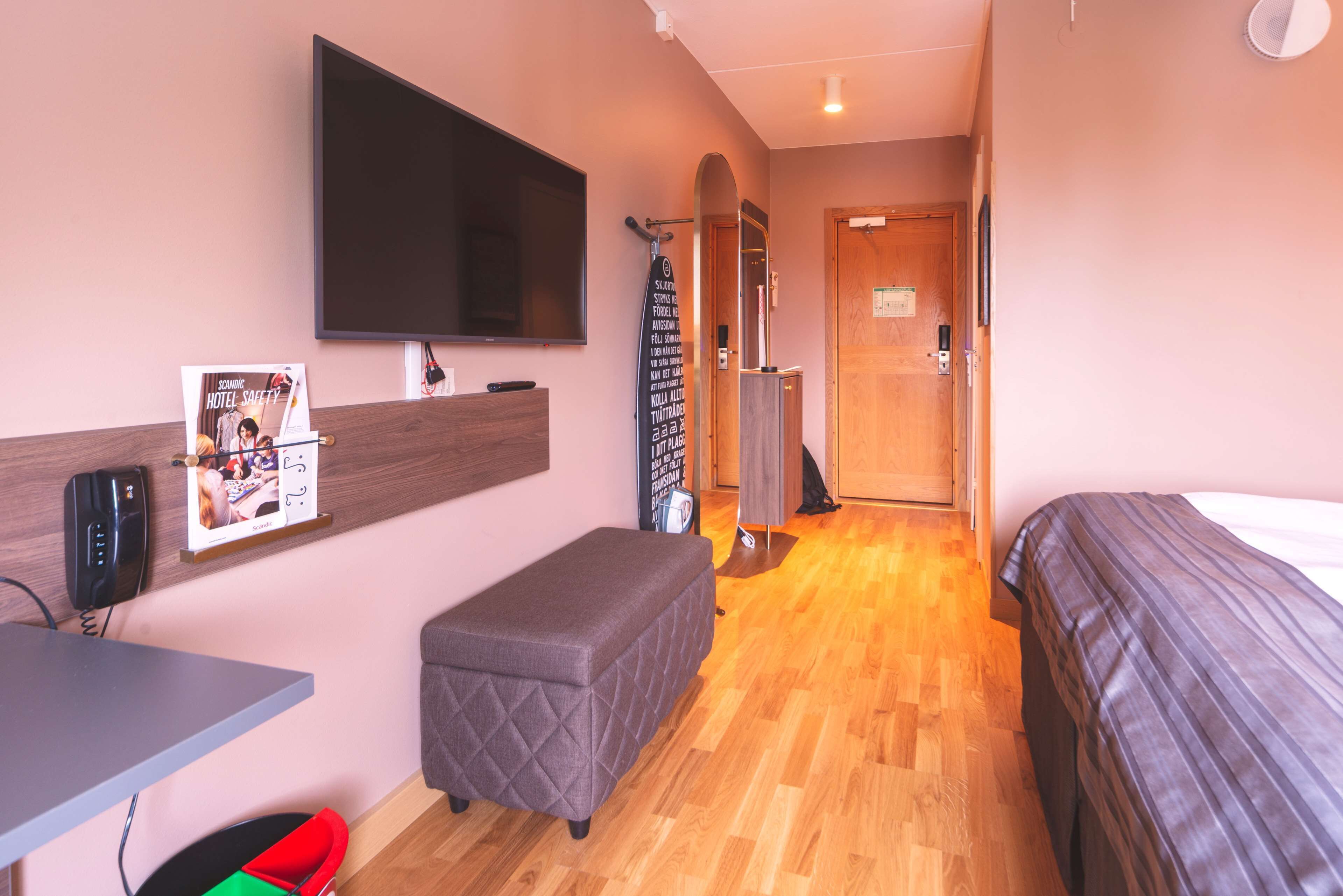 Una habitación de hotel con cama, escritorio, televisión y un pequeño rincón de descanso.