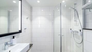 Een moderne badkamer met een douchecabine van glas, een witte wastafel met spiegel en een handdoekrek.