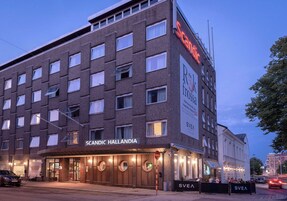 A multi-story hotel with a modern design, featuring a prominent sign for 'Scandic Hallandia' and a visible entrance with a covered area.