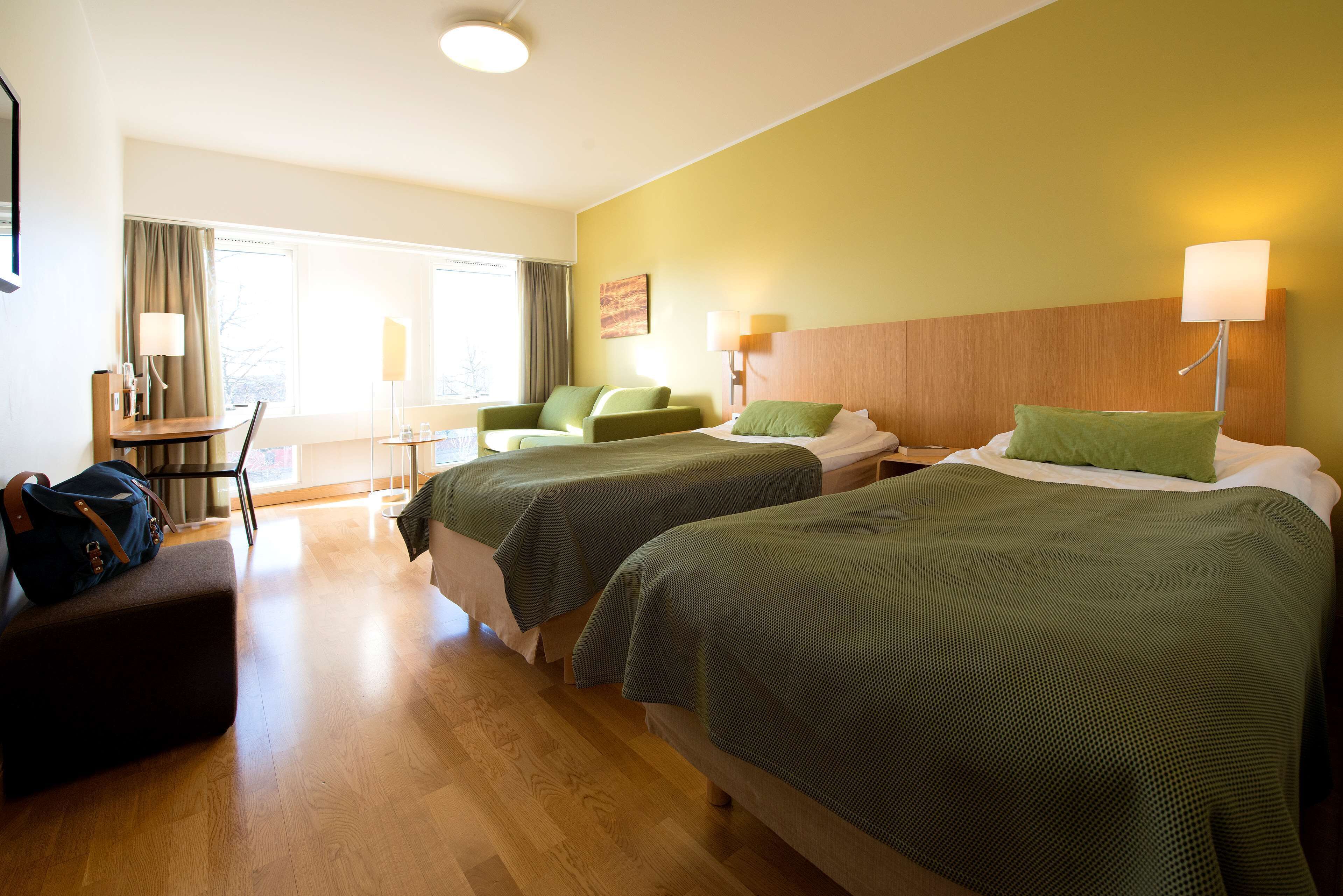 Habitación de hotel con dos camas, un escritorio y una silla.