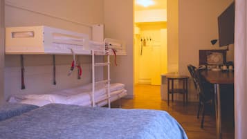 A dormitory room with bunk beds, a desk, and a chair.