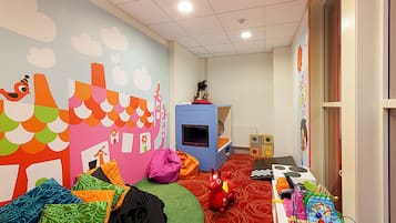 Children can play and explore in this vibrant playroom with a colorful mural, cozy seating area, and play kitchen set.
