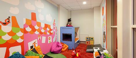 A playroom with colorful murals, a play kitchen, and a bean bag.