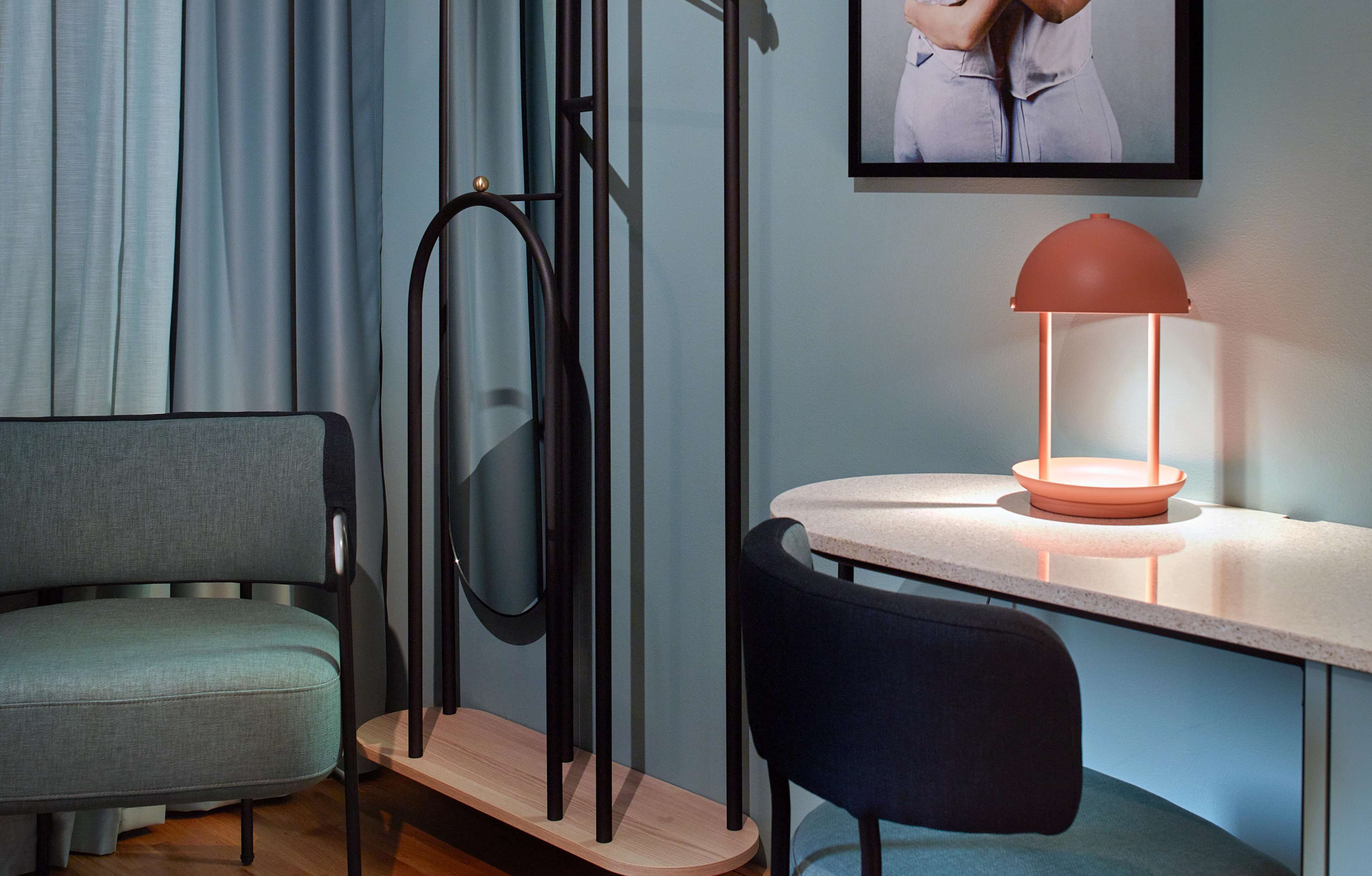 Et moderne værelse med sofa, bord, lampe og et billede i ramme på væggen.
