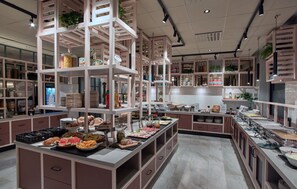 A well-organized buffet area with multiple serving stations, shelves with food items, and a clean, modern interior design. - Scandic Borlänge (Borlange)