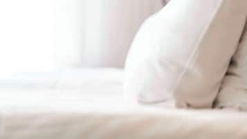 A bed with a white mattress and a white pillow.