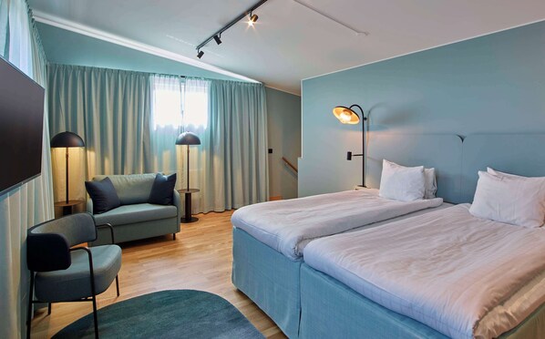A hotel room with a bed, a chair, a desk, a lamp, and a window with curtains. - Scandic Borlänge (Borlange)