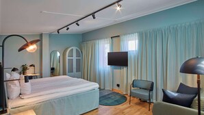 Un dormitorio moderno con una cama grande, un televisor y una zona de estar con una silla y un sofá.