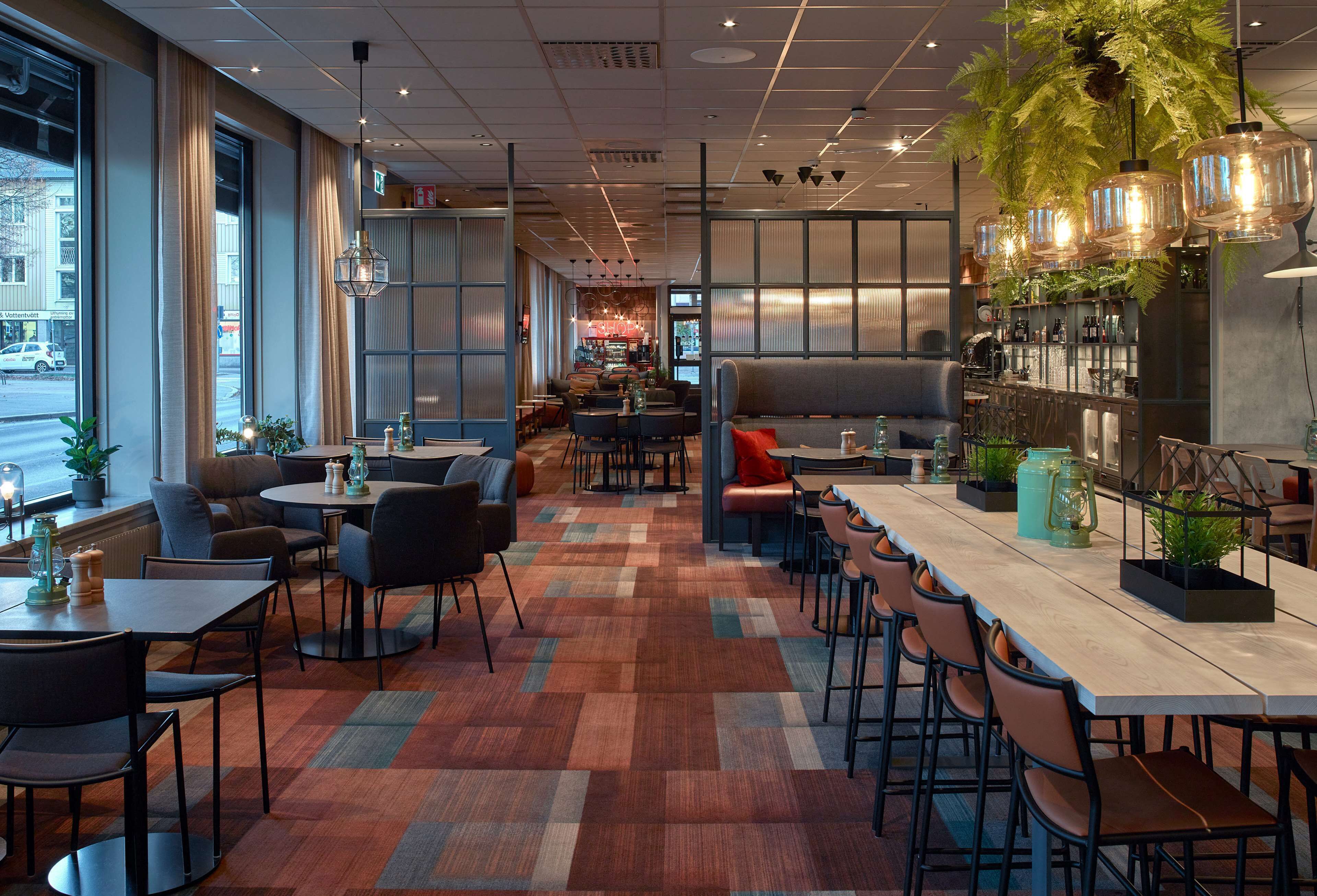 Un restaurante moderno con una mesa común alargada, varias zonas de estar y una barra.