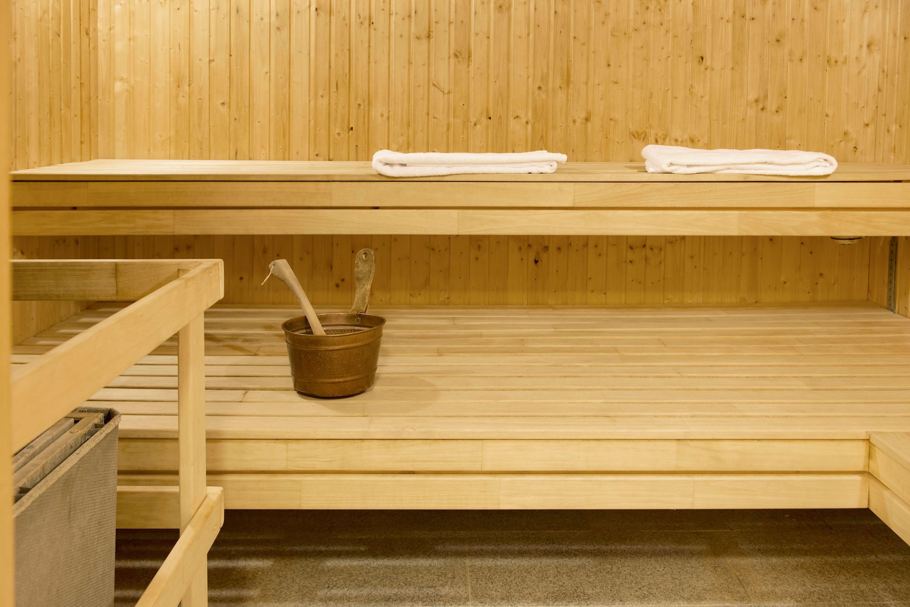 A sauna with wooden benches, a towel rack, and a bucket with a brush.
