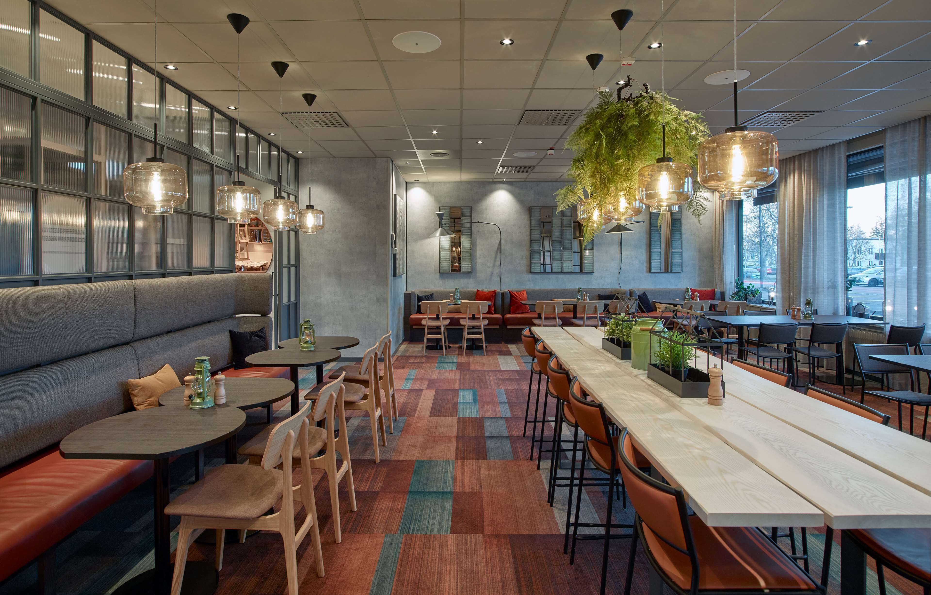 A modern restaurant with a long communal table, booths, and a variety of seating options.