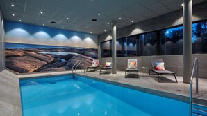 A swimming pool with lounge chairs and a mural of a rocky landscape. - Scandic Örnsköldsvik (Ornskoldsvik)