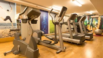 Un gimnasio con cintas de correr, elípticas y una pelota grande de ejercicio.