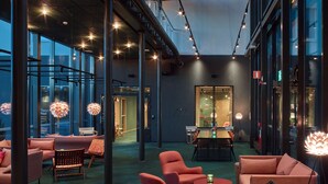 A modern interior with a high ceiling, exposed ductwork, and a mix of seating areas including sofas and chairs. - Scandic Örnsköldsvik (Ornskoldsvik)