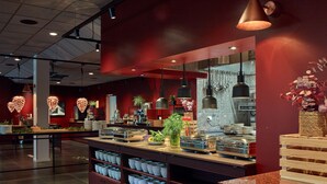 A buffet area with a variety of food items, a plant centerpiece, and a counter with bowls. - Scandic Örnsköldsvik (Ornskoldsvik)
