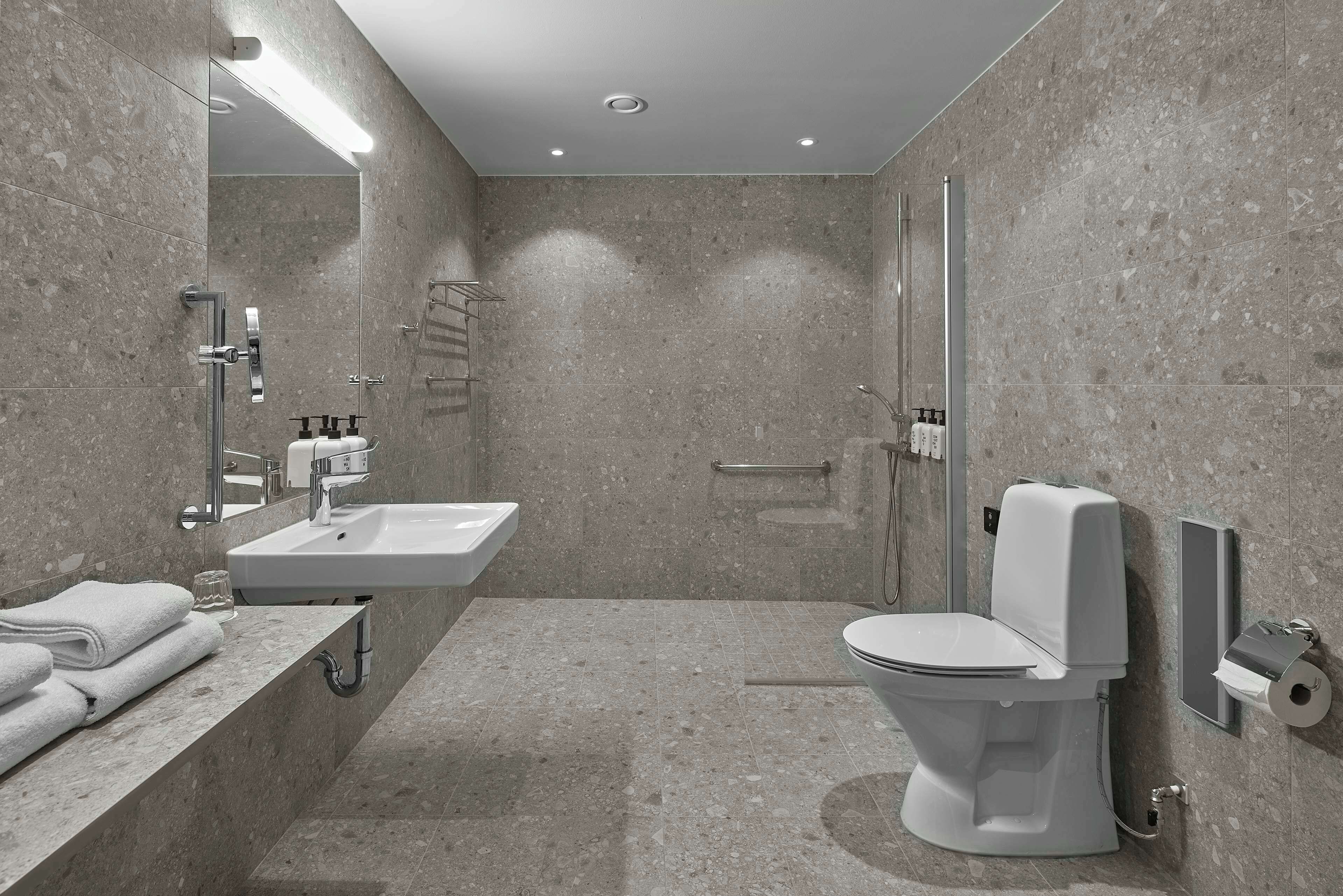 A modern bathroom with a sink, toilet, and shower.