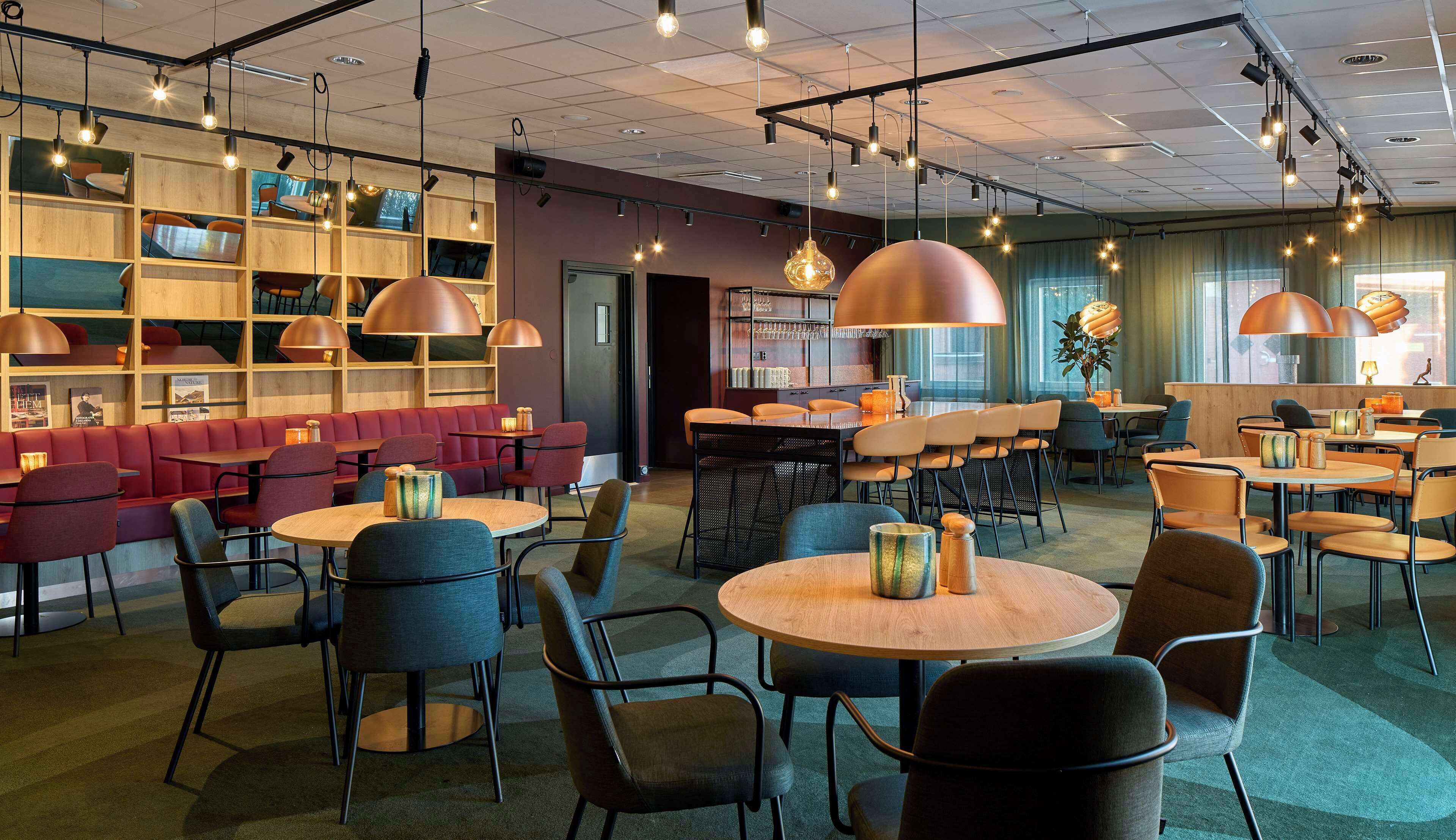 Una cafetería moderna con estantes de madera, asientos rojos y mesas redondas.