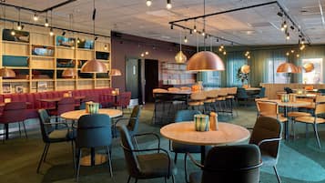 Una cafetería moderna con estantes de madera, asientos rojos y mesas redondas.